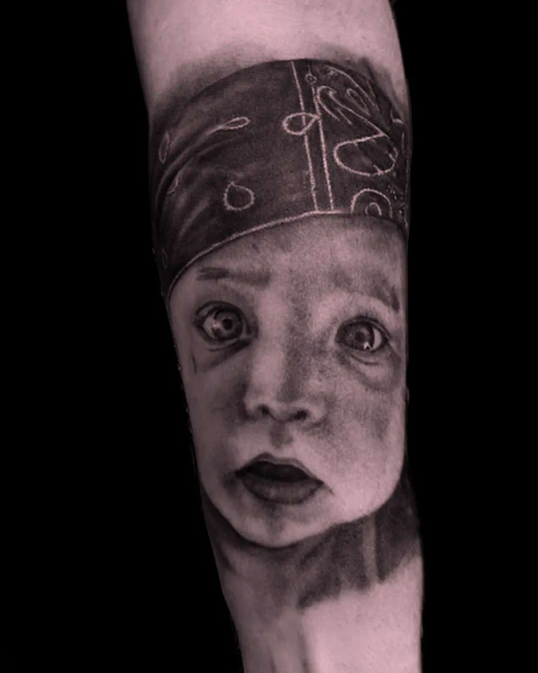 Niezwykle precyzyjny i realistyczny tatuaż portretowy przedstawiający twarz dziecka w stylu black and grey, wykonany w studio